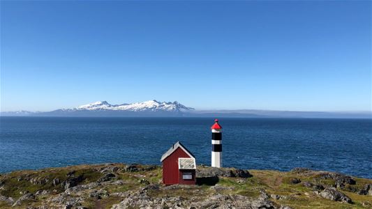 Foto av det bitte-lille fyrtårnet på Lyngstuva, med fjorden i bakgrunnen.