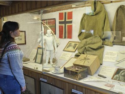 Besøkende utforsker en historisk utstilling med gjenstander fra polarhistorien i Tromsø.
