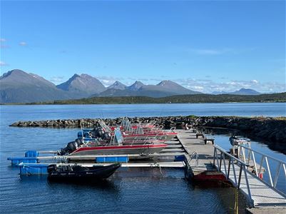Rental boats at the marina at Larseng Kystferie on Kvaløya, surrounded by fjord and mountain scenery.