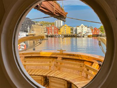 A view of Tromsø city centre and its waterfront through a round ship's window aboard the historic wooden vessel Hermes II.