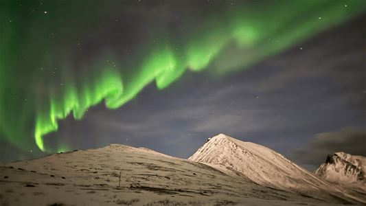 Nordlyset lyser over snødekte fjell i det arktiske landskapet rundt Tromsø.