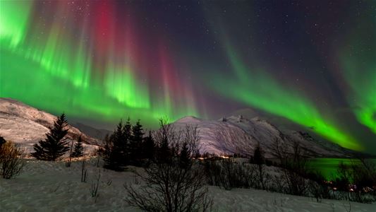 Green and red Northern lights over mountains
