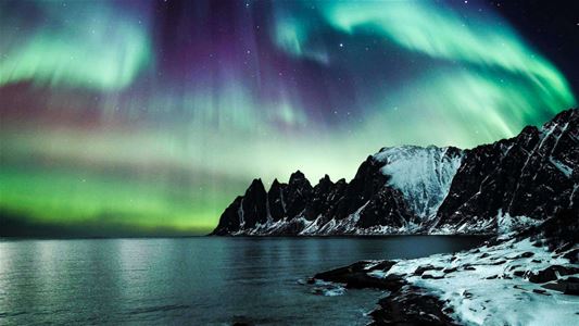 Northern lights over mountains by the coast