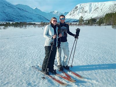 To personer med ski og staver står sammen i et snødekt fjellandskap.