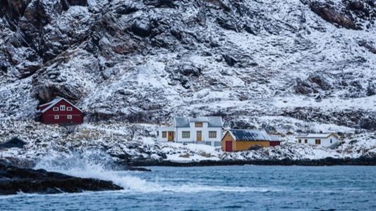 Historic coastal houses surrounded by a snow-covered landscape on Gjøssøy.