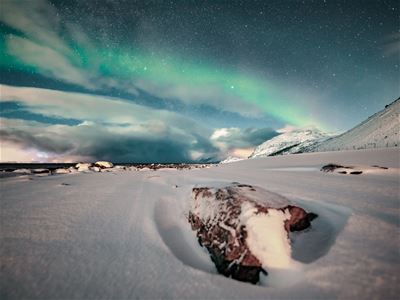 Nordlys over et snødekt fjellandskap i Lyngsalpene.