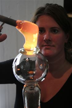 en kvinna som tillverkar något i glas