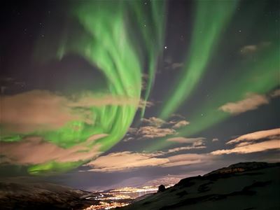 Northern Lights illuminate the sky above Tromsø and the surrounding winter landscape.