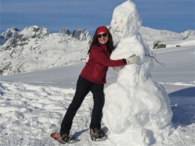 A guest takes a playful break beside a snow figure during the winter tour.