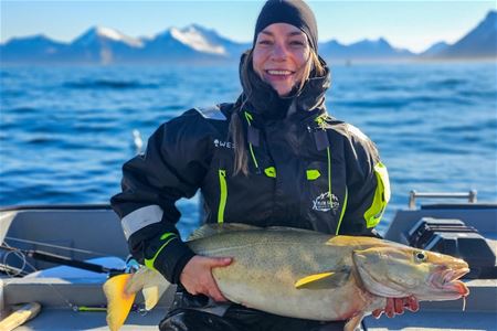 En person som holder en fisk på en båt