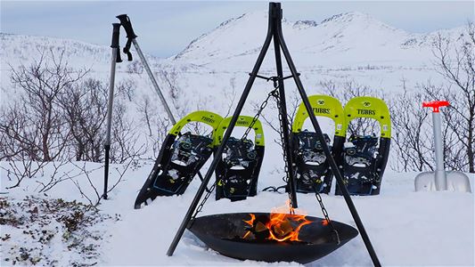 Snowshoes beside a campfire in the Arctic winter landscape of Kvaløya outside Tromsø.
