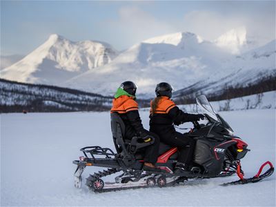 Gjester tester ut snøskuteren med fjellene i bakgrunnen