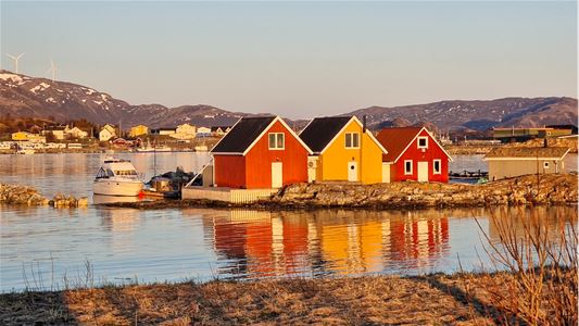 Traditional houses by the sea surrounded by mountains and Arctic coastal scenery in the Tromsø region.