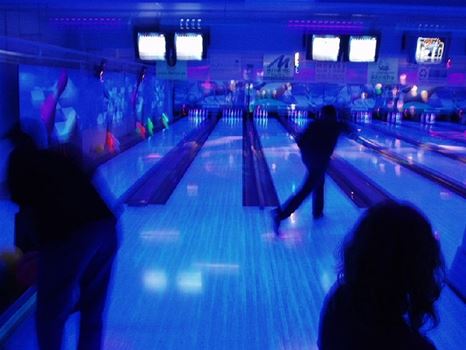 En Bowling hall med personer som spelar bowling i blått ljus