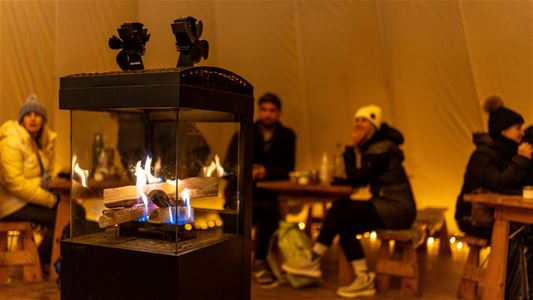 Guests gathered around the fire inside a lavvu during a cultural experience at Tromsø Lapland.
