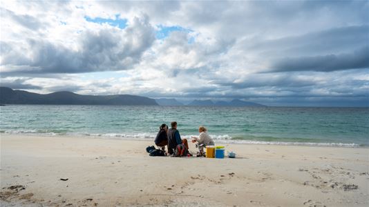 Gjestene nyter et måltid på stranden med utsikt over havet