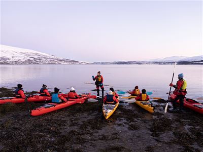 Deltakere gjør seg klare til en guidet kajakktur i vinterlandskapet på Sommarøy.