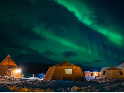 Nordlys over lavvoer og Tromsø Laplands samiske leir i vinterlandskap nær Tromsø.