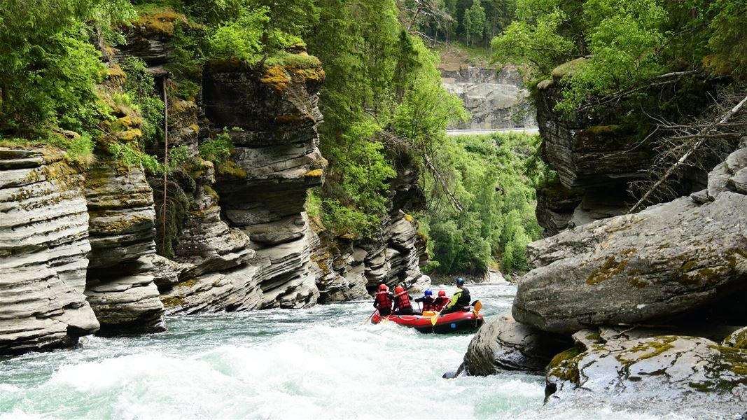 Rafting gjennom trang kløft med elv og skog.
