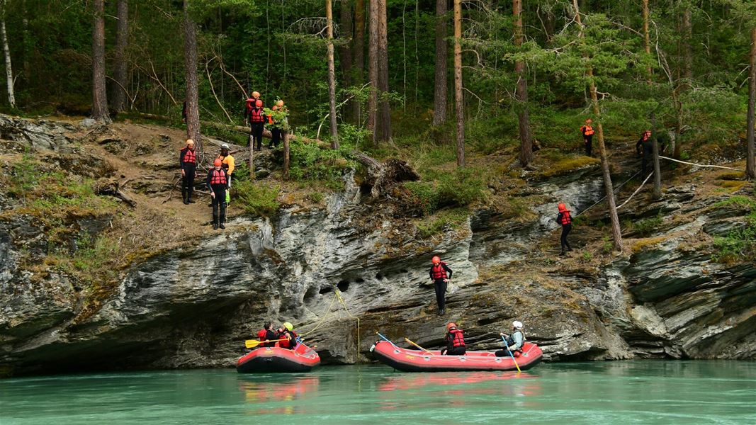 Rafting og elveaktiviteter langs en skogkledd kløft.