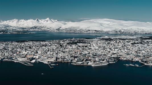 Utsikt over Tromsø med fjell og arktisk landskap i bakgrunnen.