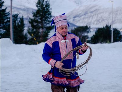 Sámi host holding a lasso at Camp Heggeli