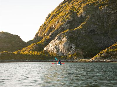 Kayaker paddling along the dramatic coastline of Sommarøy