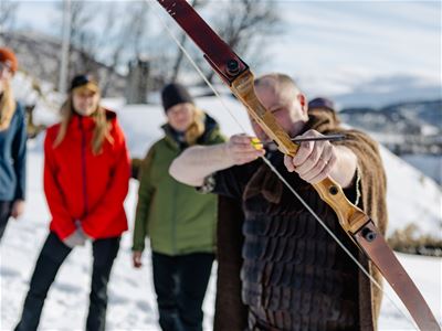 Gjest prøver bueskyting som en del av de vikinginspirerte aktivitetene under besøket nær Tromsø.
