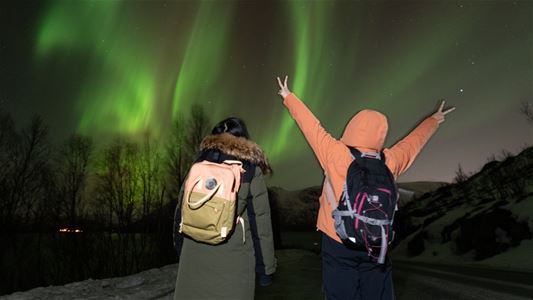 Gjester ser på nordlyset på tur med Hello Tromsø utenfor Tromsø.
