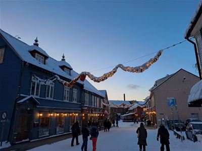 Tradisjonelle trebygninger og mennesker i Tromsø sentrum på vinterstid.