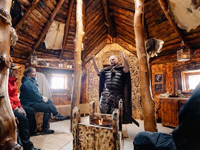 Visitors gather inside a handcrafted Viking building to hear stories about Viking life, traditions and craftsmanship.