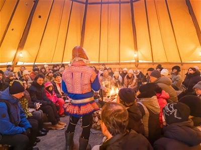Gjester samlet i en tradisjonell lavvo for å lære mer om samisk kultur og historie i Tromsø.