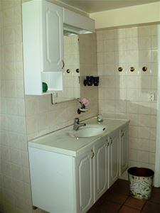 White washstand with beige tiled walls. 