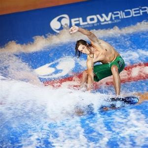 A guy rides a surfboard in foamy water.