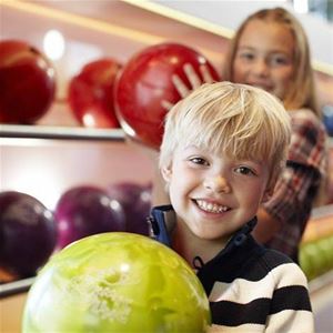 Two children are picking up a bowling ball.