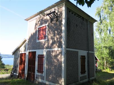 Ett fyrkantigt mindre tegelbyggnad med röda dörrar. 