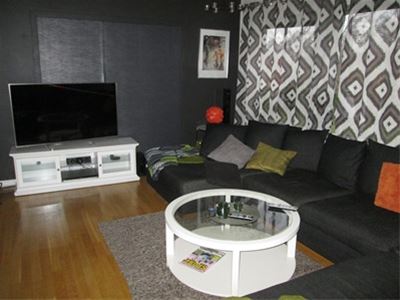 Black sofa, white, round table and teve in a dark room. 