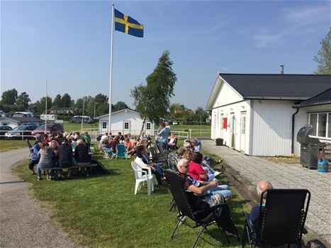 Människor som sitter på en gräsplätt under en Sverigeflagga