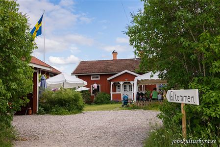 Farm image with red house, flagpole with Swedish flag.