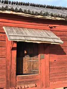 An old red timber building, a low door that stands open.
