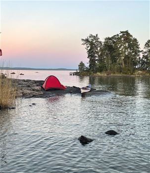 Tält på skärgårdsö med kajak bredvid