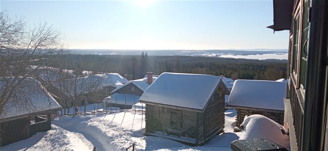 Vinterbild med hus och härbren med snö på taken. 
