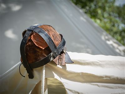 En hjälm av stål hänger på ett tält.