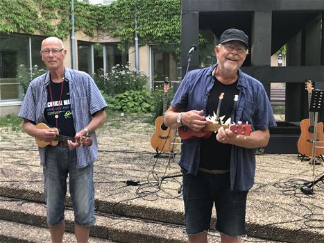 Två män som står och spelar ukulele