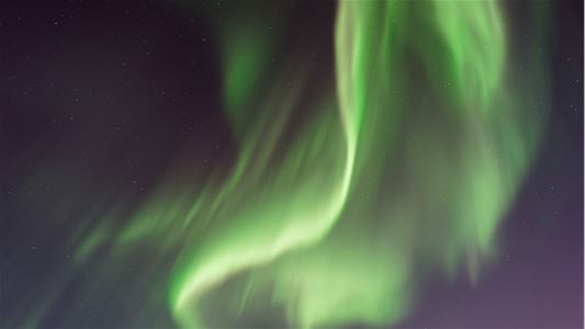 Grønt nordlys danser over den mørke arktiske nattehimmelen.