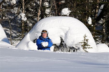 En person sitter och solar vid en snöhög. 
