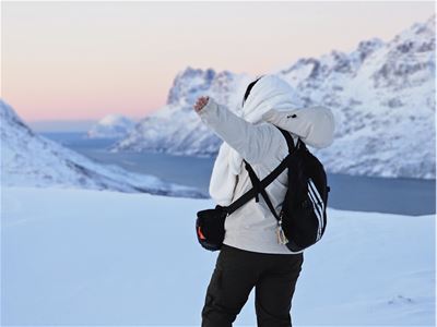 Guest photographing the snowy fjord and mountain scenery during a winter tour in the Tromsø region.